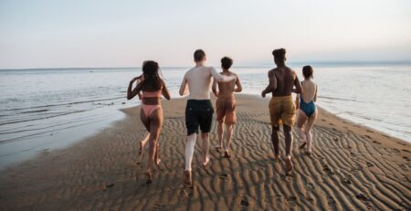 Un groupe d'amis courant sur la plage, illustrant les expériences authentiques en mode slow travel et tourisme durable.